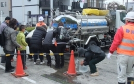 給水拠点で市民が給水車から水をくんでいる写真
