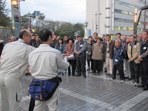 庁舎前で市職員による放射能測定方法の説明を聞く参加者の写真